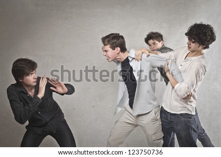 Two guys are quarreling, one of these is held by two friends