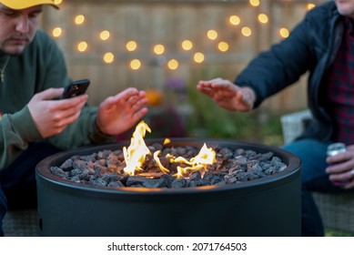 Two Guys Sitting Around A Backyard Fire Pit In Autumn