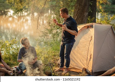 two guys are talking camp stories to each other near the tent in wonderful nature