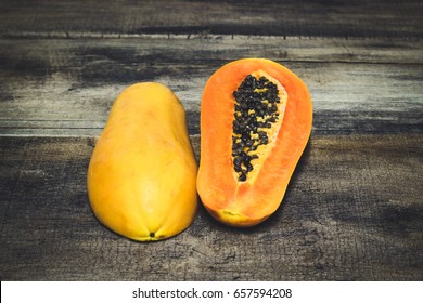 Two half cutted ripe papayas on old wooden