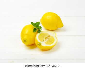 two and half lemons on white wooden background