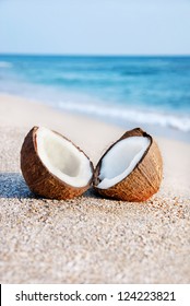 two halfs of coconut against sea at the sea sand beach