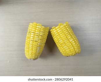Two Halves of Cooked Sweet Corn on Light Wooden Surface