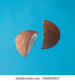 Two Halves Of Fresh Coconut In The Air On The Blue Summer Background. Abstract Art. Minimal Creative Decoration.