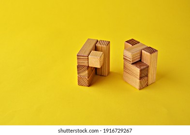 Two Halves Of A Wooden Cube Logical Game On A Yellow Background With A Copy Space. Solving Logical Problems. High Quality Photo