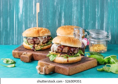 Two Hamburgers With Beef Burger Cutlet, Fried Onion, Spinach, Ketchup Sauce And Blue Cheese In Traditional Buns, Served On Wood Chopping Board Over Bright Turquoise Background. Copy Space