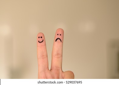 Two hand drawn emoticon faces persons fingers   one happy   smiling   the other unhappy  sad depressed isolated neutral background and copy space