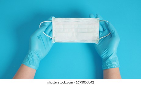 Two Hand With Gloves And Face Mask For Protection From Virus Infection. Put On Blue Background.