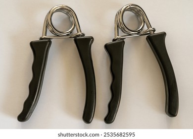 Two hand grippers on white background. Used for strenghening the hand and arm muscles by squeezing them. - Powered by Shutterstock