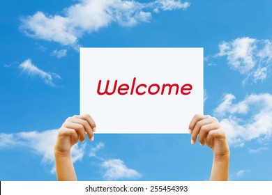 Two hand holds a sign for the  welcome