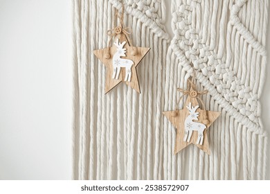 Two handcrafted wooden star ornaments featuring reindeer are suspended against a textured macramé wall. The rustic decor adds a festive touch to any space. - Powered by Shutterstock