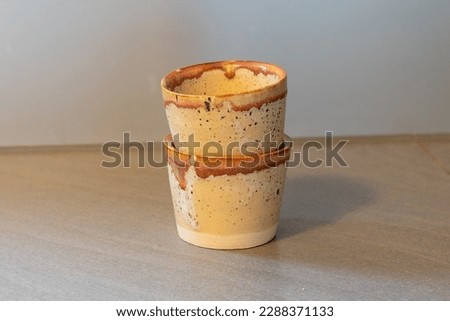 Two handmade coffee cups coated in sandstone glaze and green