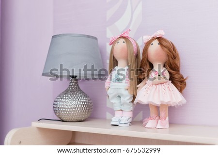 Two handmade dolls with natural hair are on the nightstand next to a vintage lamp