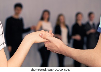 Two Hands Against The Background Of A Group Of People. Mutual Aid And Support.