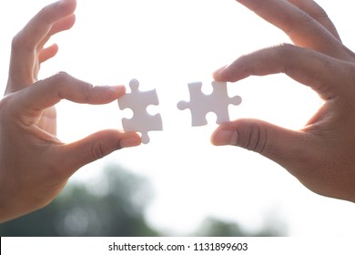 Two hands assembling jigsaw puzzle pieces, with sky background. Teamwork concept. - Shutterstock ID 1131899603