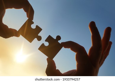 zwei Hände Geschäftsmann zu verbinden Puzzle-Stück mit Himmel Hintergrund.Jigsaw allein hölzernes Rätsel gegen Sonnenstrahlen.ein Teil des ganzen.Symbol der Verbindung und Verbindung.Geschäftsstrategie