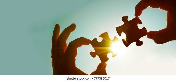 zwei Hände Geschäftsmann zu verbinden Puzzle-Stück mit Himmel Hintergrund.Jigsaw allein hölzernes Rätsel gegen Sonnenstrahlen.ein Teil des ganzen.Symbol der Verbindung und Verbindung.Geschäftsstrategie