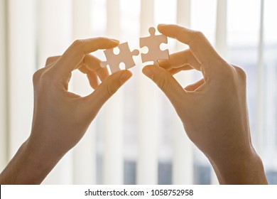 Two hands of businessmen help each other to fill the gap of the jigsaw to make job completely done.