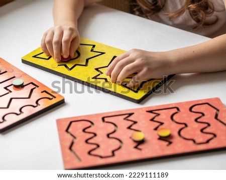 Two hands of a child with an interhemispheric board on a white table, correctional classes for children with speech disorders or neurology.