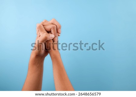 Two Hands Clasped And Raised Isolated On Blue Background.