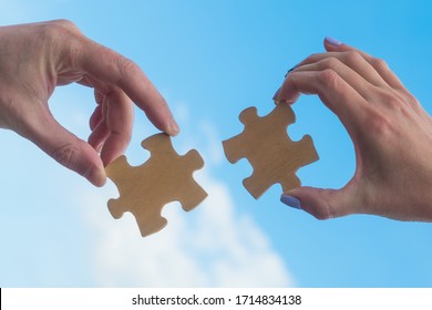 Two hands connect puzzle pieces against the sky. Business concept idea, cooperation, partnership, teamwork, innovation