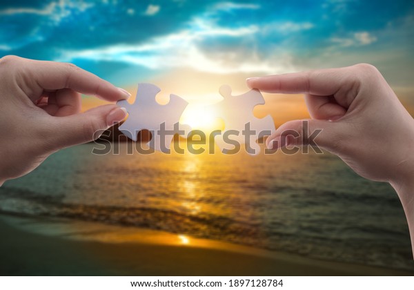 Two hands\
connect puzzle pieces against the sky. Business concept idea,\
cooperation, partnership, teamwork,\
innovation