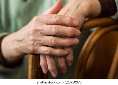 two hands of an elderly woman sitting on a chair