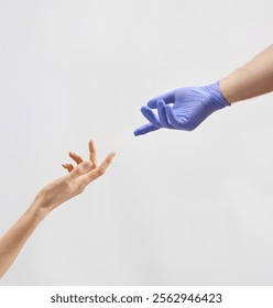 Two hands are extended towards each other, one bare and the other gloved, symbolizing a moment of connection and support in a medical setting.