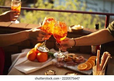 Two hands with glasses of Aperol spritz cocktail