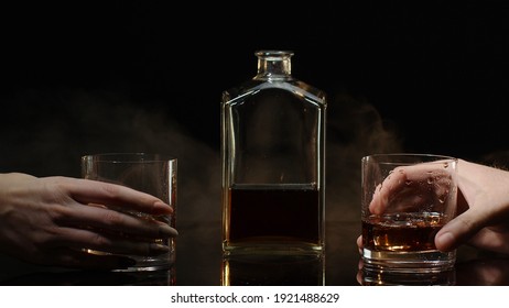 Two Hands With Glasses Of Cognac Whiskey With Ice Cubes Making Cheers On Black Background. Celebration Of Business Success, Christmas, Anniversary, Birthday. Raising Toast With Glasses Of Brandy, Rum