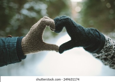 Two Hands In Gloves Holding Love Heart Symbol In Winter Forest