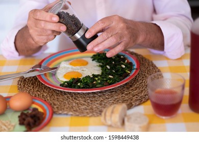 Two Hands Grind The Pepper Over The Eggs. Recipe With Spinach, Raisins And Pine Nuts. Healthy Eating