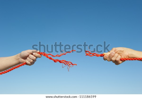 Two hands\
gripped around broken orange rope leaving a gap, isolated with blue\
sky as background and copy\
space.