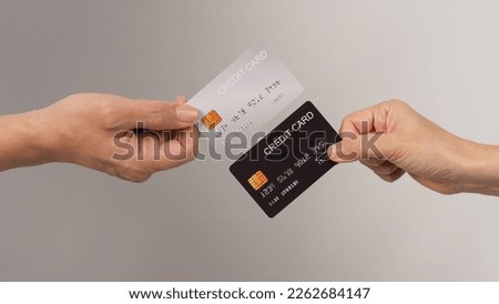 Two hands is hold black and silver credit card on white background.	