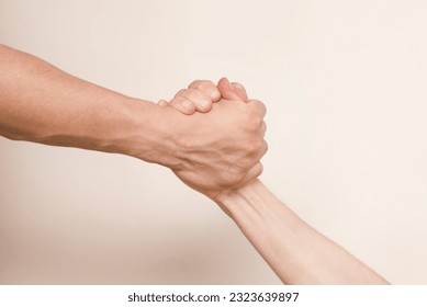 Two hands hold tightly to each other, rescuer saves, pulls out of trouble a person in need of help, the concept of helping someone in need, selective focus - Shutterstock ID 2323639897
