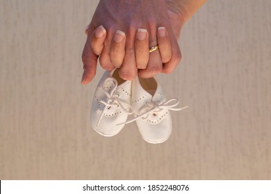 Two hands holding baby shoes. pregnancy concept.