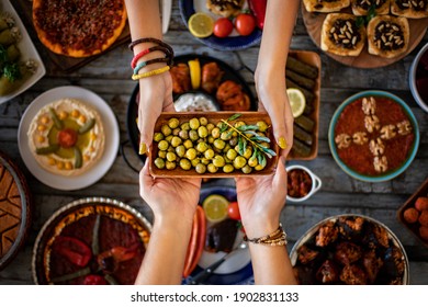 Two women’s hands holding green marinated olive fruits in a bowl. Sharing foods concept. - Powered by Shutterstock