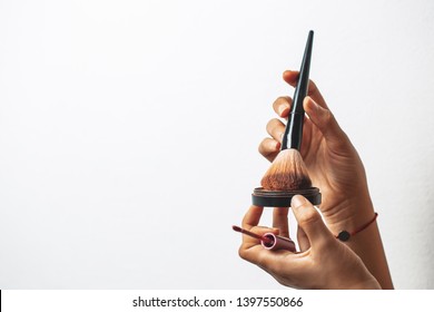 Two Hands Holding Makeup Brushes In Isolated Background