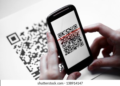 Two hands holding a mobile phone scanning a QR code