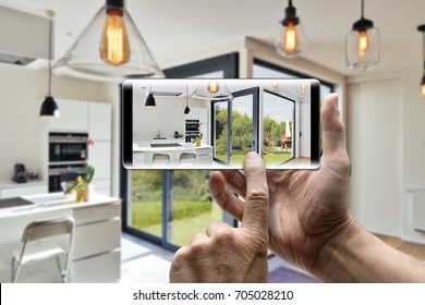 Two Hands Holding A Mobile Smartphone And Take A Picture In A Modern Luxury Living Room And Kitchen