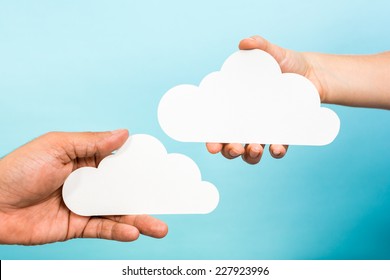 Two Hands Holding Paper Clouds On Blue Background. Cloud Computing Concept.
