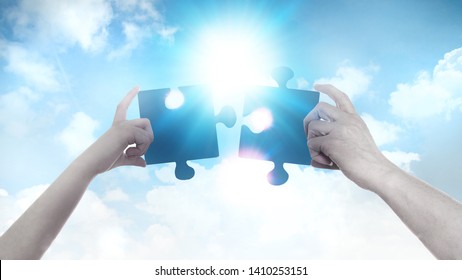 Two hands holding a puzzle pieces agains of blue sky background and sun. Business, support, finding the right decision concept.  - Shutterstock ID 1410253151
