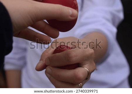 Two hands holding red Easter eggs about to tap them together, traditional Romanian Easter custom. Symbolic Orthodox holiday ritual.