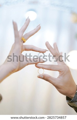 Two hands holding separate wedding rings against a bright, soft and minimal background. The image represents marriage, love, commitment, partnership and human relationships, while the distance between the rings can also suggest separation, relationship challenges or divorce. The high-key lighting, soft focus and subtle bokeh create an elegant and emotional atmosphere. This vertical conceptual image is suitable for wedding invitations, marriage websites, relationship articles, jewelry advertising, engagement content, romantic campaigns, counseling materials, and lifestyle publications. The clean background provides useful negative space for text and graphic design.                