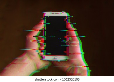 Two hands holding smartphone, mobile phone facing up, closeup. Glitches, distorted, corrupted image with colorful lines on the phone and hands. Color channels effect.