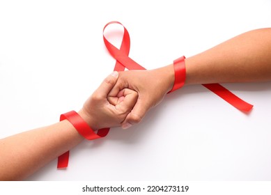 Two hands holds each other with red ribbon. Aids day concept - Shutterstock ID 2204273119