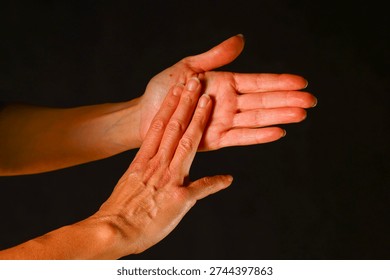 Two hands interacting in a gentle touch, showing connection, communication and the subtle emotional meaning conveyed through human contact and expressive movement - One open hand faces upward while the other presses softly against the palm. The interaction suggests communication, reassurance and the subtle emotional language expressed through touch. The gesture highlights sensitivity, presence and human connection.