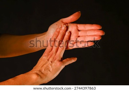 Two hands interacting in a gentle touch, showing connection, communication and the subtle emotional meaning conveyed through human contact and expressive movement - One open hand faces upward while the other presses softly against the palm. The interaction suggests communication, reassurance and the subtle emotional language expressed through touch. The gesture highlights sensitivity, presence and human connection.
