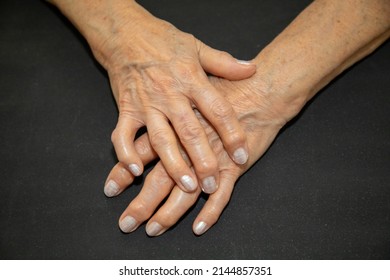 two hands of an old woman on a black table. Isolated on a white background. top view