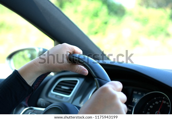 Two hands on\
the steering wheel of a fast\
car
